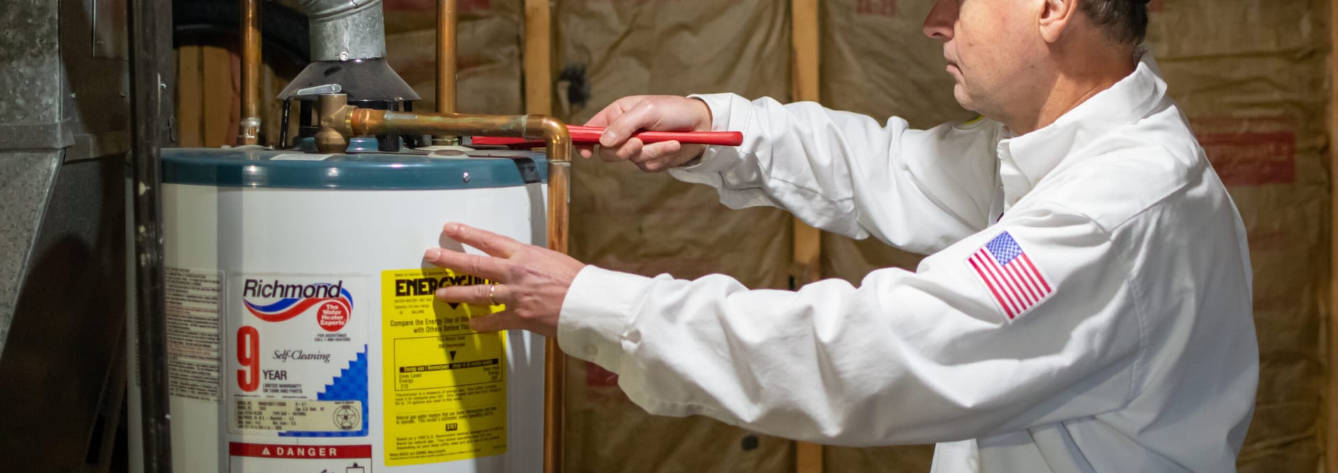 Technician in protective gloves servicing the control panel and valves of a water heater tank